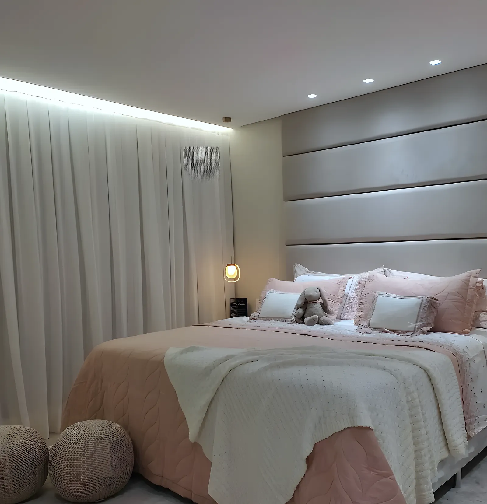Cabeceira estofada cinza em painéis horizontais altos em quarto de casal rosê, em Lauro de Freitas