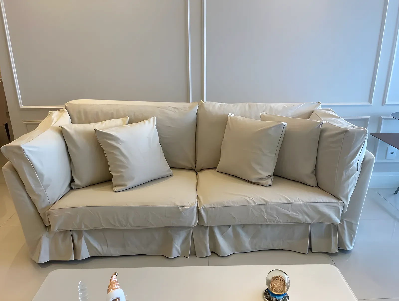Capa de sofá bege sob medida com saia e almofadas no mesmo tecido, na sala de estar, em Salvador