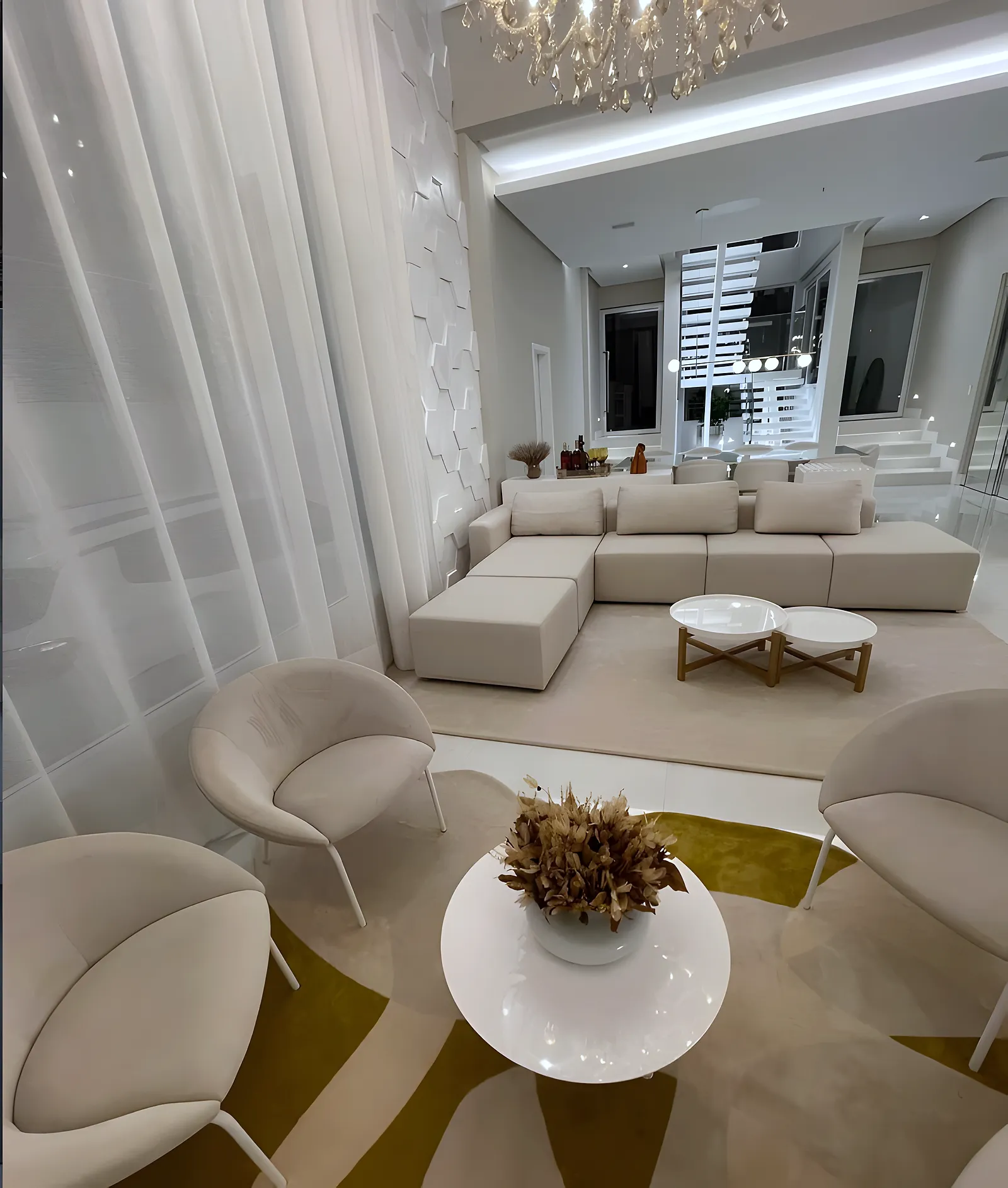 Tapete orgânico mostarda e bege sob poltronas e tapete bege sob o sofá em sala de pé-direito duplo, em Salvador